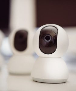 Close-up of three smart home security cameras placed on a white desk indoors.